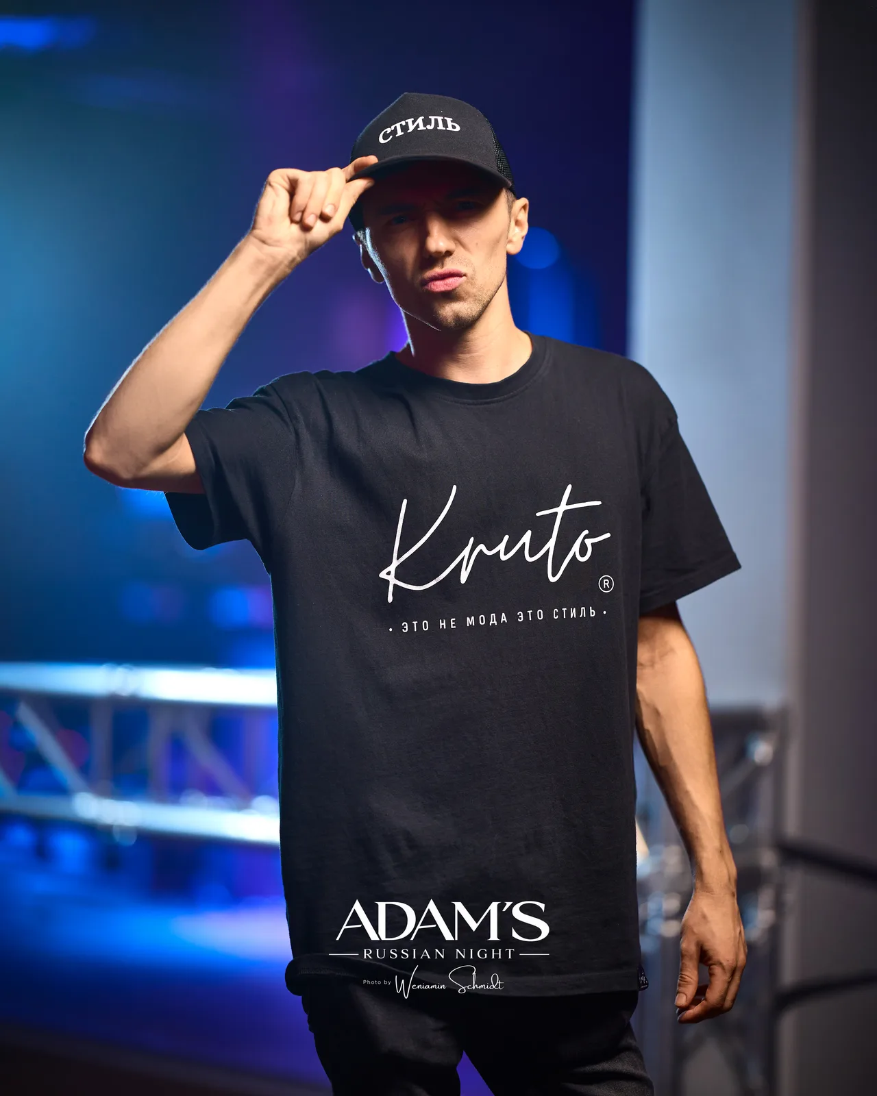 Mann mit Kruto-Shirt und Cap mit der Aufschrift СТИЛЬ vor der Bühne
